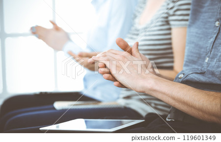 Business people clapping at meeting or conference, close-up of hands. Group of unknown businessmen and women in modern white office. Success teamwork, corporate coaching and applause concept 119601349