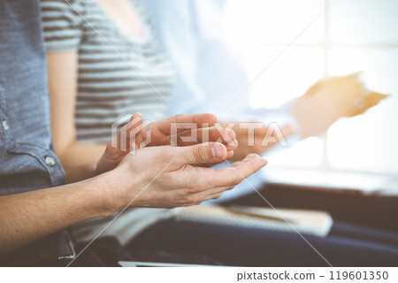 Business people clapping at meeting or conference, close-up of hands. Group of unknown businessmen and women in sunny office 119601350