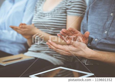 Business people clapping at meeting or conference, close-up of hands. Group of unknown businessmen and women in modern white office. Success teamwork, corporate coaching and applause concept Business people clapping at meeting or conference, close-up of hands. Group of unknown businessmen and women in modern white office. Success teamwork, corporate coaching and applause concept 119601352