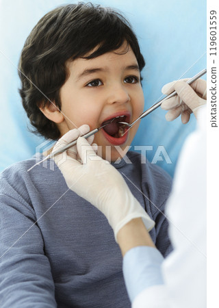 Little arab boy sitting at dental chair with open mouth during oral checking up with dentist doctor. Stomatology concept 119601559