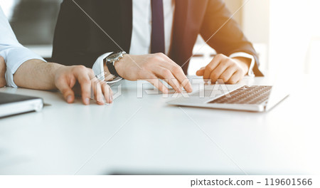 Unknown business people using laptop computer at the desk in modern office. Businessman or male entrepreneur is working with his colleague. Teamwork and partnership concept 119601566