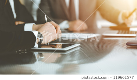 Unknown businessmen and woman sitting, using laptop computer and discussing questions at meeting in sunny office, close-up. Success concept 119601577