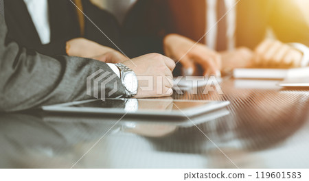 Unknown businessmen and woman sitting, using laptop computer and discussing questions at meeting in sunny office, close-up. Success concept Unknown businessmen and woman sitting, using laptop computer and discussing questions at meeting in sunny office, close-up. Success concept 119601583