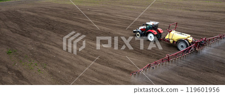 field and tractor spraying grain 119601956