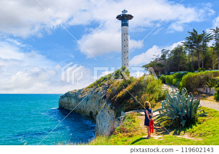 Woman in blue dress walking on the path that leads to Torredembarra Lighthouse 119602143