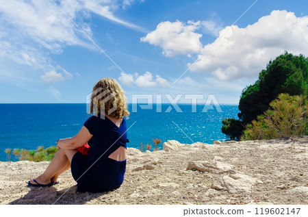 Curly-haired blonde woman looking at the sea in Torredembarra, Tarragona 119602147
