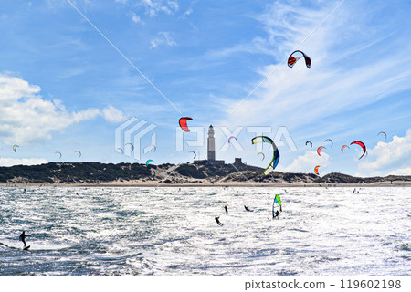 Los Canos de Meca, Barbate, Cadiz; August 19, 2022: athletes practicing kitesurfing in front of the beach of the Trafalgar Lighthouse 119602198