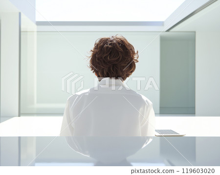 Person with brown hair sitting at a modern minimalist desk Person with brown hair sitting at a modern minimalist desk 119603020