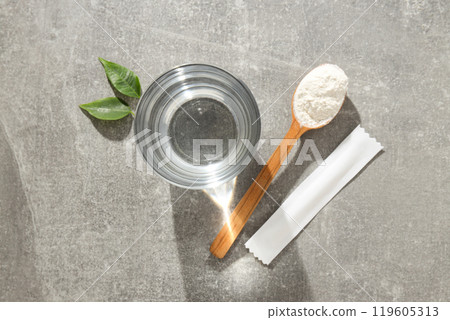 Collagen powder in a wooden spoon with a glass of water 119605313