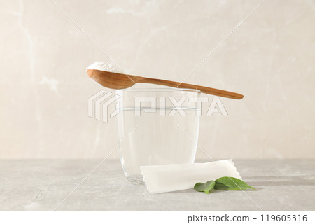 Collagen powder in a wooden spoon with a glass of water 119605316