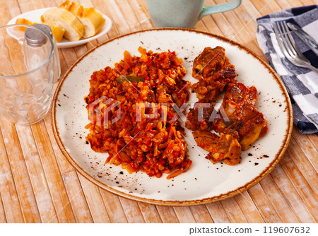 Few fried pork ribs are on plate with side dish of stewed cabbage with pearl barley porridge Few fried pork ribs are on plate with side dish of stewed cabbage with pearl barley porridge 119607632