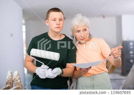 Guy helps his grandmother to renovate the room during holidays. Grandma points with her finger what to do Guy helps his grandmother to renovate the room during holidays. Grandma points with her finger what to do 119607695
