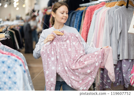 Positive female customers shopping in clothing store with warm clothing Positive female customers shopping in clothing store with warm clothing 119607752