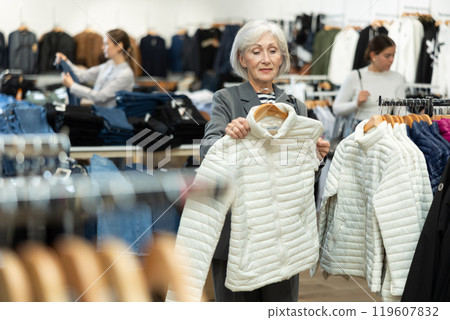 Elderly woman chooses jacket in store Elderly woman chooses jacket in store 119607832