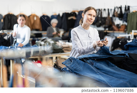 Middle-aged woman choosing jean pantaloons in clothing store 119607886