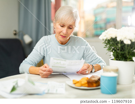 Senior woman with financial documents at home 119607910