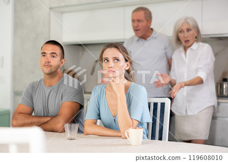Portrait of an offended married couple in home kitchen, which mature family members reprimand. Family conflict Portrait of an offended married couple in home kitchen, which mature family members reprimand. Family conflict 119608010