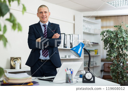 Office worker standing in workplace and looking in camera 119608012