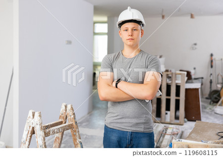 Portrait of a fifteen-year-old teenager with a roller and a paint tray in his hands 119608115