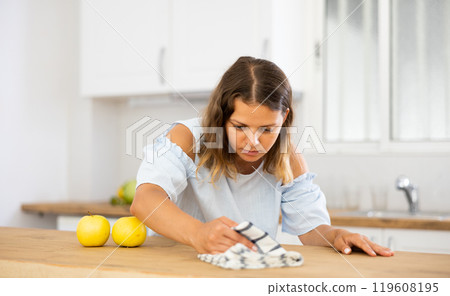 Positive woman cleaning kitchen table at home Positive woman cleaning kitchen table at home 119608195