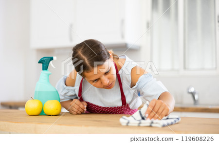 Positive woman cleaning kitchen table at home 119608226