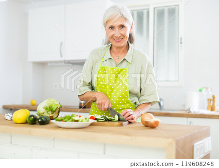 Mature woman cutting fresh vegetables for dinner Mature woman cutting fresh vegetables for dinner 119608248