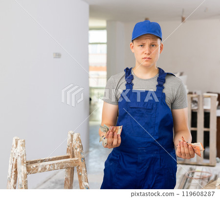 Frustrated fifteen-year-old worker counts his first salary Frustrated fifteen-year-old worker counts his first salary 119608287