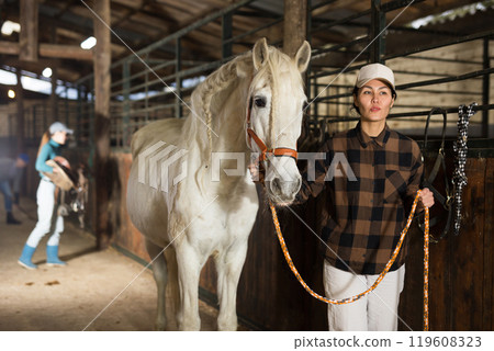Portrait of asian woman with white horse in stable 119608323