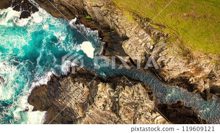 Stunning Aerial View of Vibrant Turquoise Waves Elegantly Crashing Against Rocky Shoreline Stunning Aerial View of Vibrant Turquoise Waves Elegantly Crashing Against Rocky Shoreline 119609121