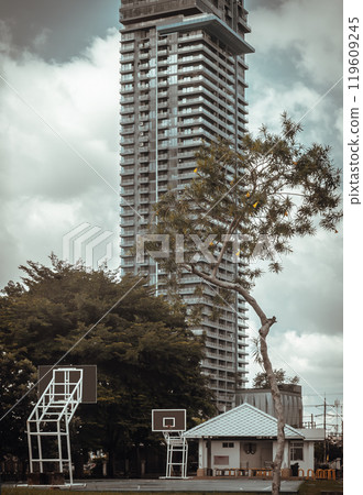 Basketball backboard with the hoop metal ring in basketball court at the park with High Rise condominium building background. 119609245