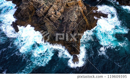 Stunning Aerial View of Vibrant Turquoise Waves Elegantly Crashing Against Rocky Shoreline 119609395