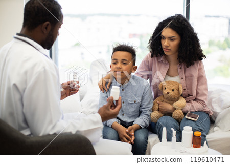 Doctor examines young boy with mother offering medication for recovery 119610471