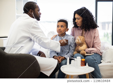 Doctor examining sick boy with mother in hospital room Doctor examining sick boy with mother in hospital room 119610484
