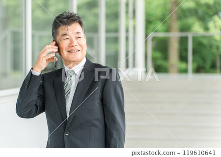 Senior male businessman in a suit talking on a smartphone Senior male businessman in a suit talking on a smartphone 119610641