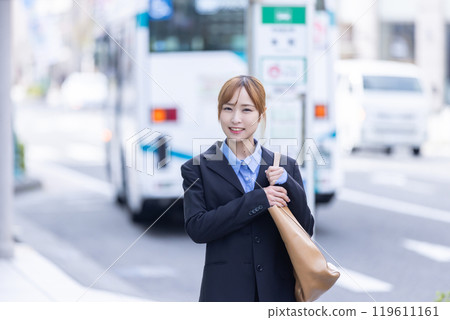 Businesswoman smiling in front of a bus stop 119611161