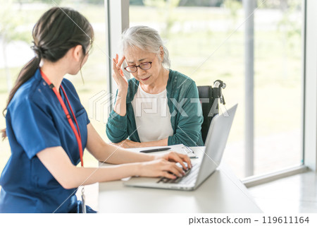 An elderly woman (fatigue, eye strain, high blood pressure) and a female nurse consulting about feeling unwell and headaches 119611164
