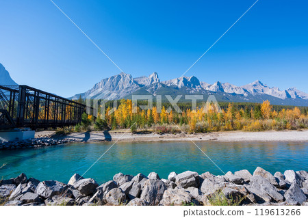Canadian Rockies autumn landscape. Mount Rundle mountain range and trees reflected on the Bow River. Canmore, Alberta, Canada. Canmore Engine Bridge. 119613266