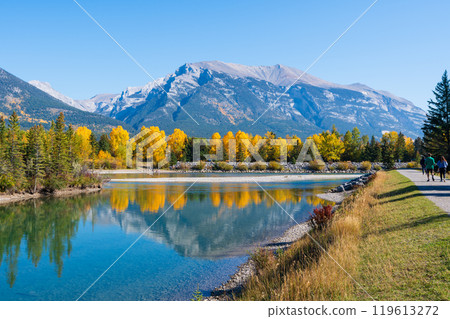 People are walking along the Bow River riverside trail in autumn. Canmore, Alberta, Canada. Rundle Plante Lane. 119613272