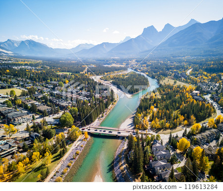 Aerial view of Town of Canmore residential area and Bow River in autumn sunny day. Canadian Rockies mountain range in background. Alberta, Canada. 119613284