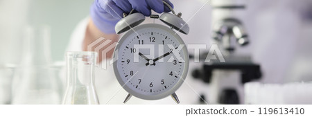 Scientist in gloves measures time for conducting experiment Scientist in gloves measures time for conducting experiment 119613410