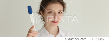 Smiling young brunette woman shows electronic thermometer 119613420