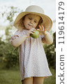 Joyful Girl in a Dress and Straw Hat, Holding an 119614179