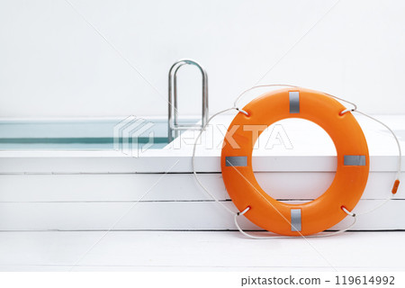 An orange lifebuoy is by the pool. summer concept An orange lifebuoy is by the pool. summer concept 119614992