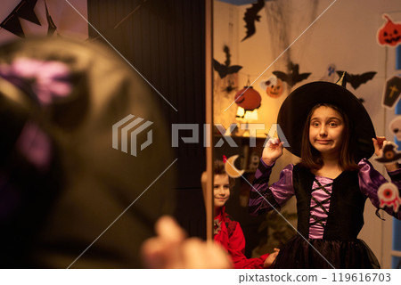 Girl in witch costume looking in mirror Girl in witch costume looking in mirror 119616703