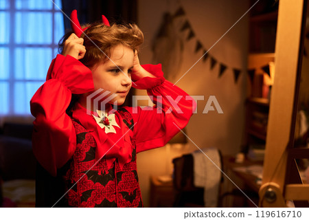 Boy putting on headband with red horns Boy putting on headband with red horns 119616710