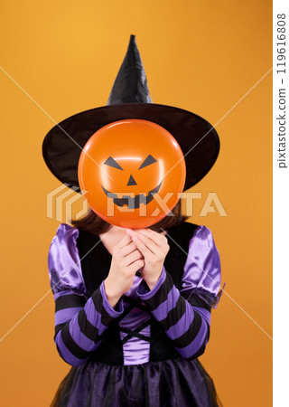 Witch hiding behind pumpkin balloon 119616808