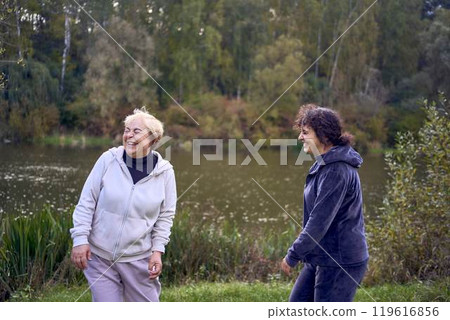 middle-aged woman and her old mother laughing during a morning jog together, for maintaining health by the river in autumn 119616856