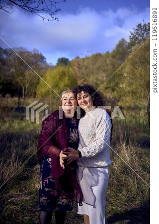 middle-aged daughter and elderly mother together on a walk in the autumn forest middle-aged daughter and elderly mother together on a walk in the autumn forest 119616891