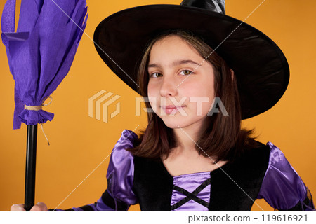 Smiling youthful witch with purple broom Smiling youthful witch with purple broom 119616921