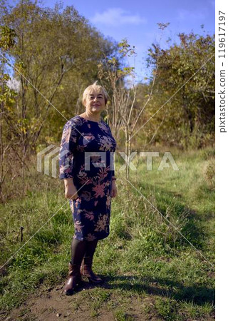 a   portrait of an elderly woman with gray hair in a dress  in the autumn forest 119617197